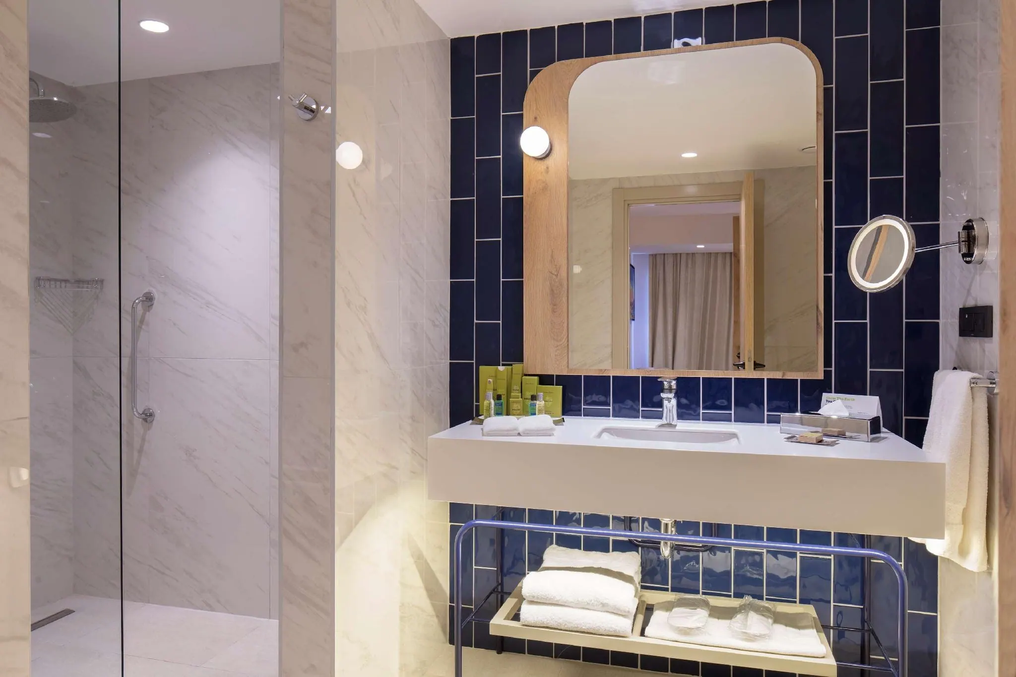 Guest bathroom with navy vertical tile, a timber-framed mirror and walk-in shower